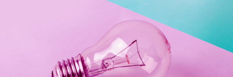 A close-up of a light bulb, with a pink and green background